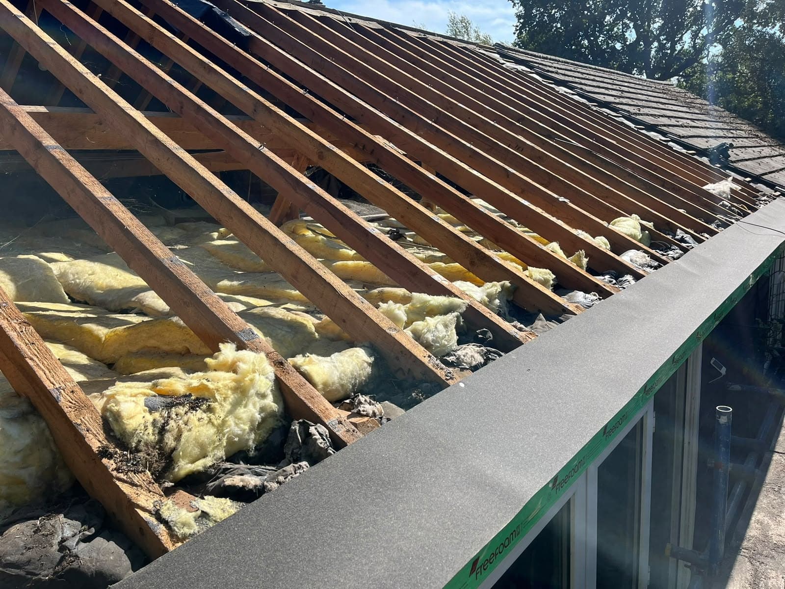 Old roof stripped back above a conservatory